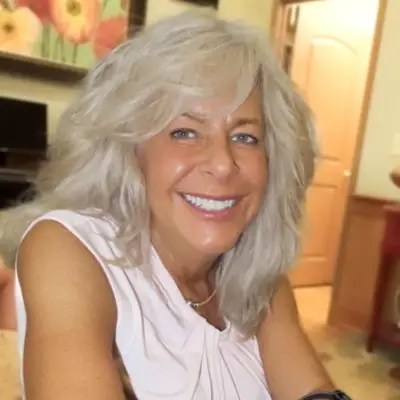 Smiling woman with long, wavy hair indoors.
