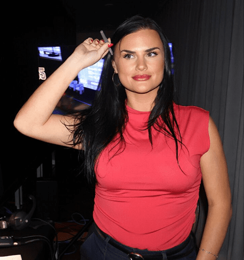 Woman in red top holding a cigarette.