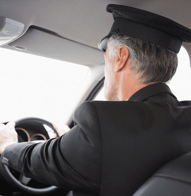 Chauffeur driving car, viewed from backseat.