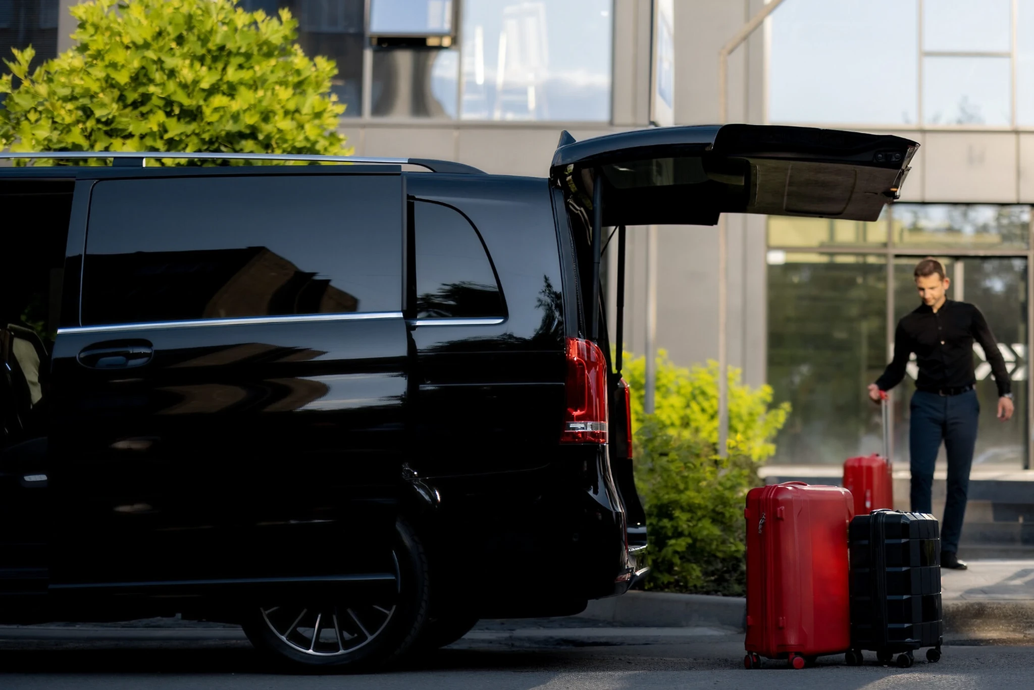 Black van with open trunk, red suitcases.